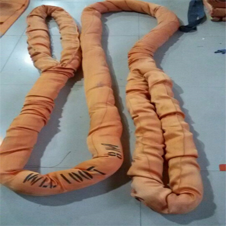 Two orange sleeved round slings folded on a tiled floor with a working load limit printed in black along the woven
 cover of one