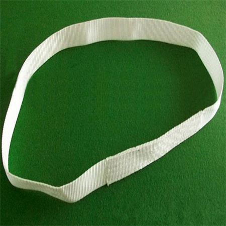 A white flat woven webbing sling closed into a loop, its woven face and its joined section both in view, laid on a
green surface