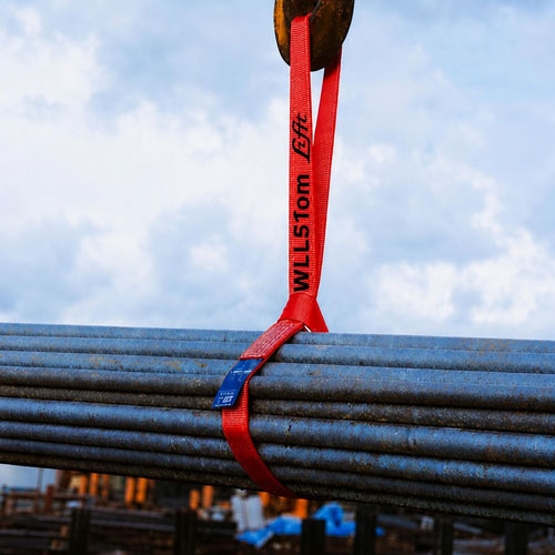Disposable pre-slung cargo sling rigged on a steel pipe bundle and taken up on a crane hook in a yard