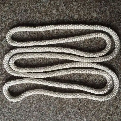 The endless braided coupling rope photographed by the maker: the white braided rope laid out in a serpentine of four passes on a dark speckled stone floor, showing the over and under braid along its length, with no printed marking and no fitting attached