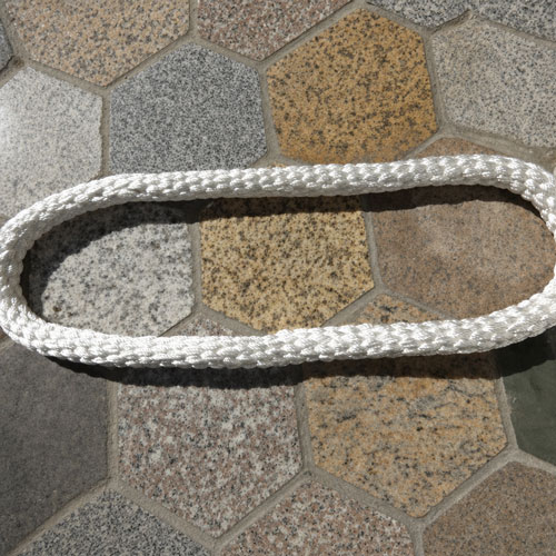 The endless braided coupling rope photographed by the maker on a paved surface: a white braided rope closed into a long flat loop, the braid running unbroken through both turns, with no splice, no stitching, no tape and no fitting anywhere on the loop